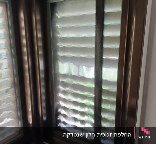 חלון זכוכית עם מסגרת מתכת בפינת חדר